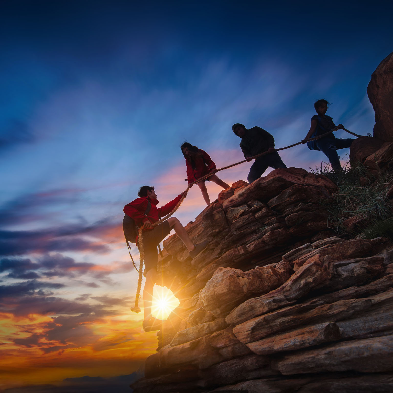 Hikers climbing up on the mountain at sunset ,teamwork and helping concept.