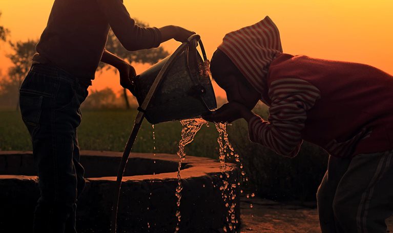 Children drinking water on water well