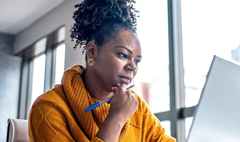Black woman working from home office and looking pensively at her computer screen