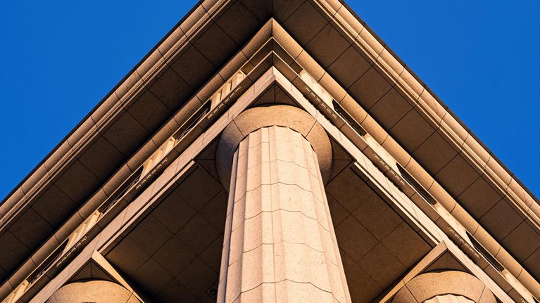 The exterior of a government building with large columns supporting the roof. The building is made of stone and has a classical architectural style.