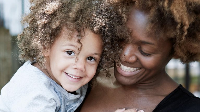 Smiling woman holding a happy child.