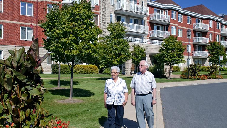 A senior couple walking outdoors in a senior living community.