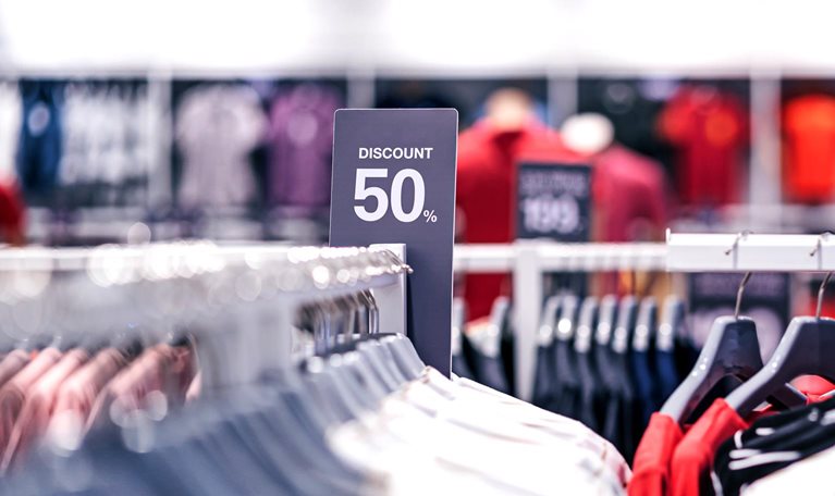 Discount 50% label of sales tag price over the clothes line in a shopping department store.