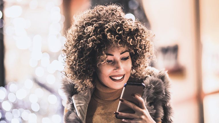 Woman using smartphone and holding shopping bag