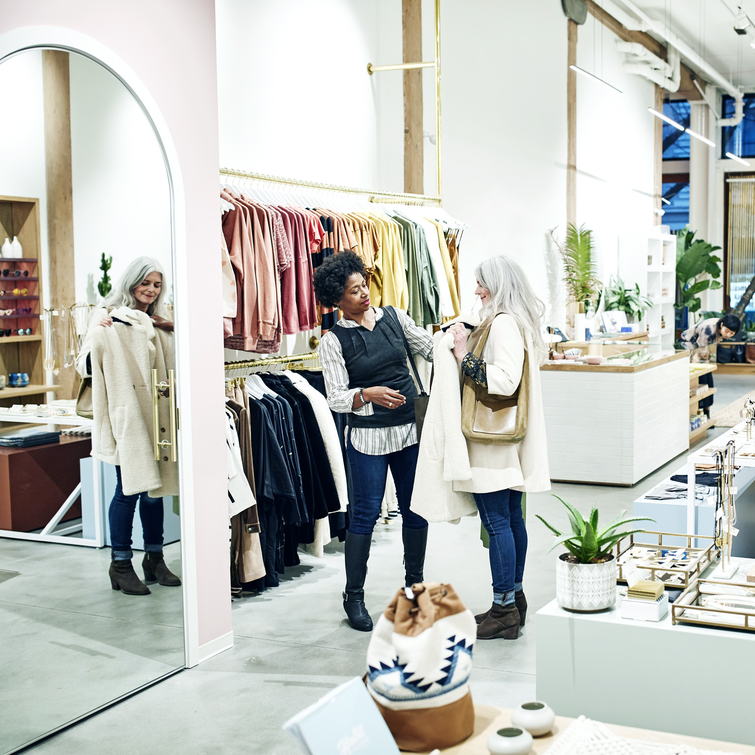 Female friends shopping together in clothing boutique.