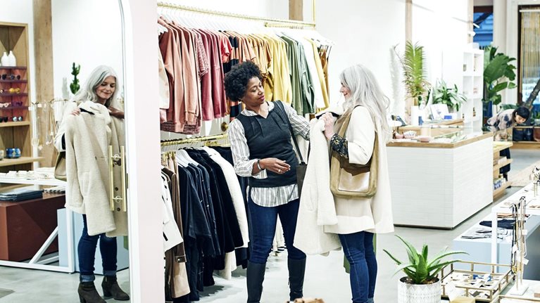Female friends shopping together in clothing boutique.