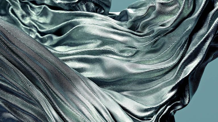 Fabric with a textured surface gracefully flowing and swirling in the air, creating dynamic folds and curves.