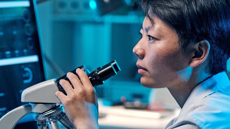 Young serious female scientist looking at computer screen