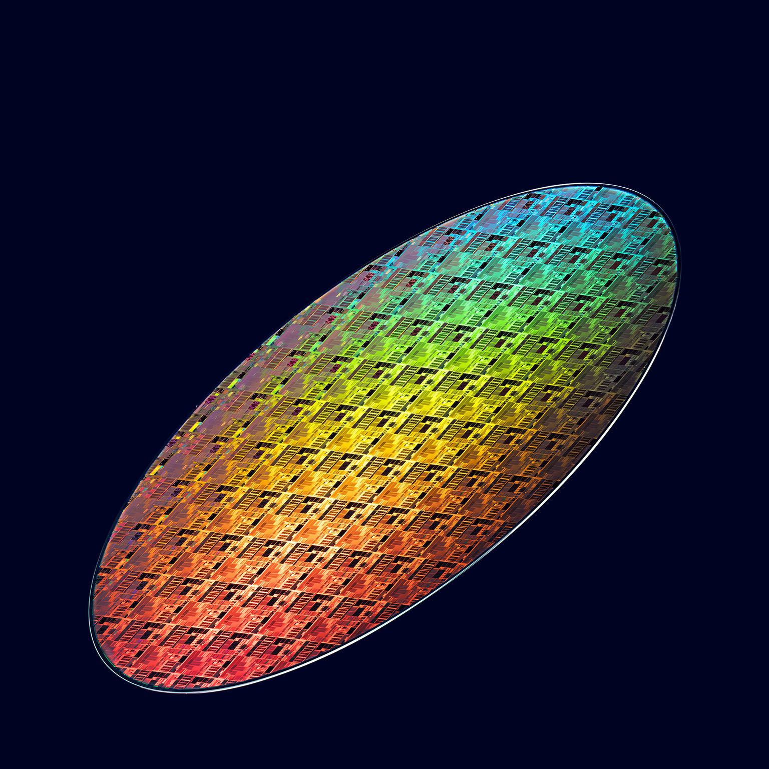 Colorful iridescent semiconductor wafer with intricate microchip patterns displayed against a dark background.