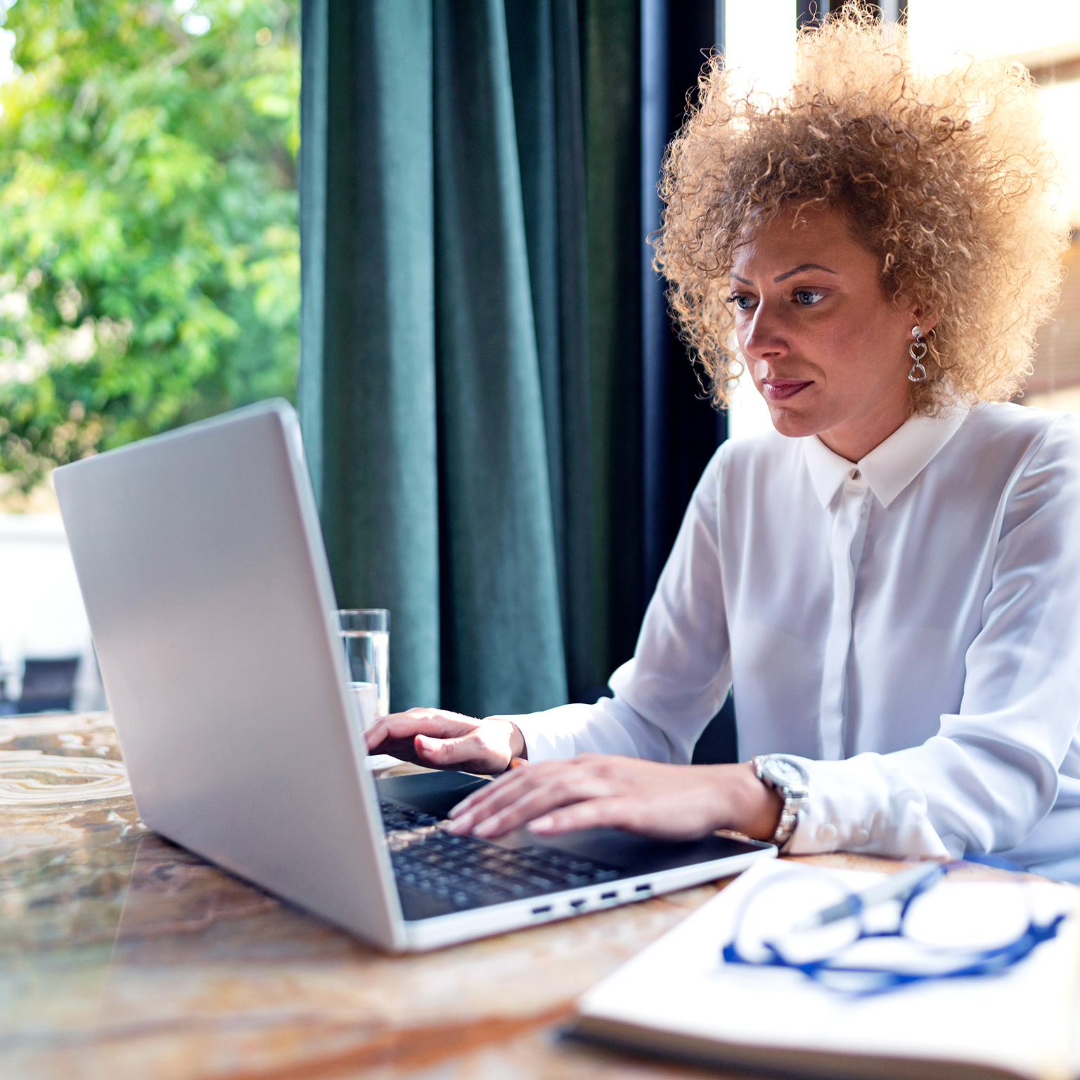 Freelancer working on her laptop at the restaurant - stock photo