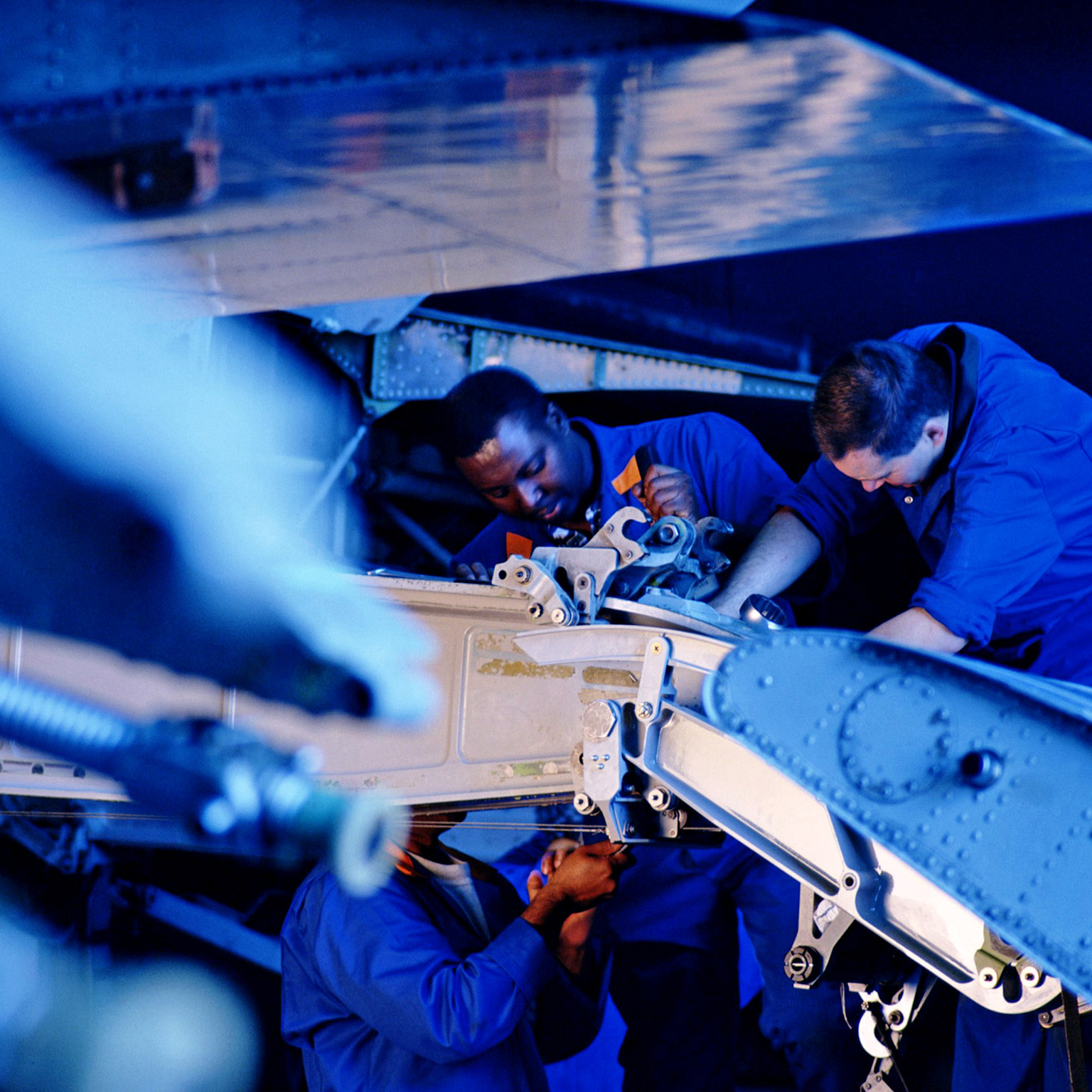 Flight engineers working on wing flap of airplane