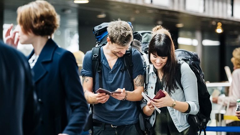 Young backpacker couple waiting at check in counter at the airport - stock photo