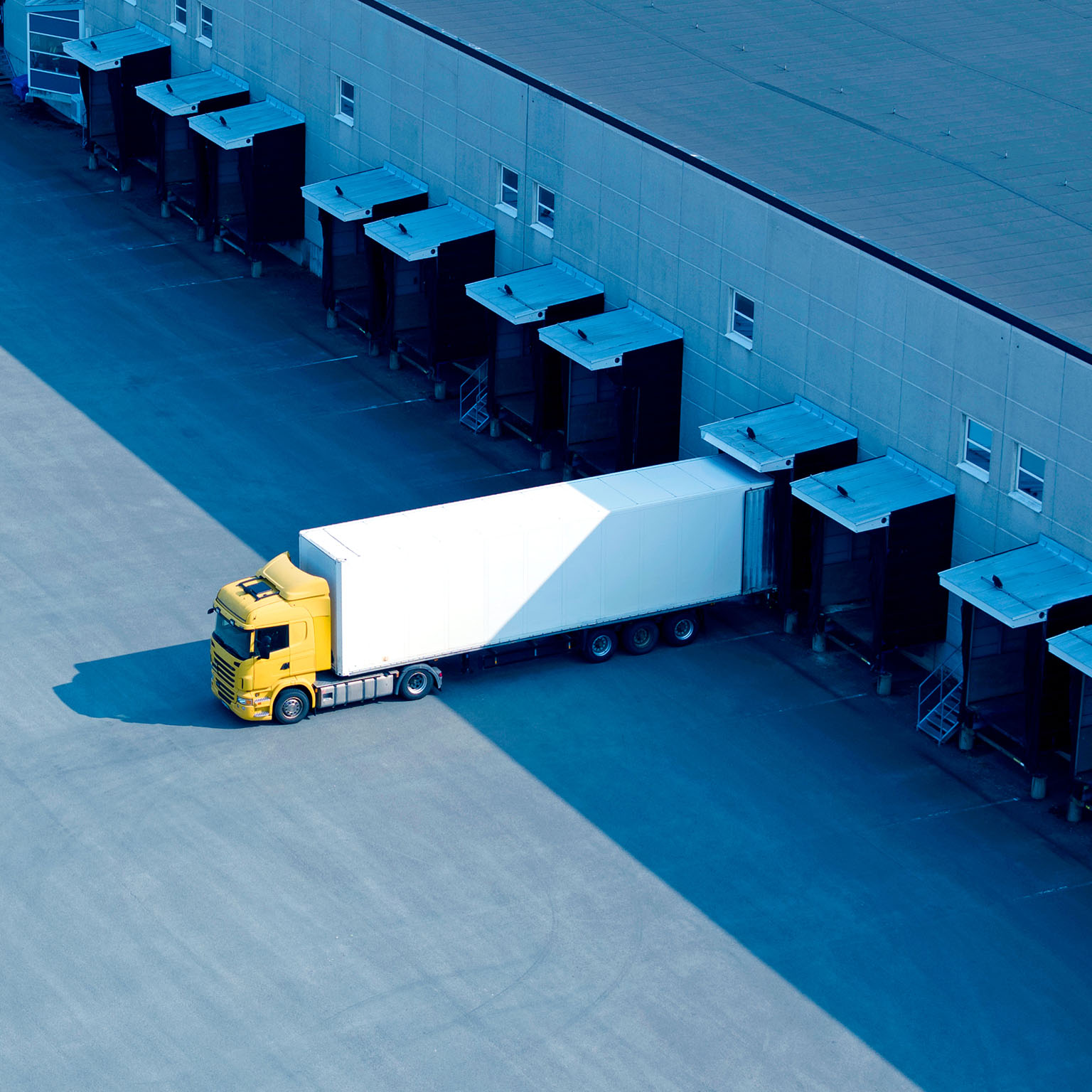 A single truck at the loading docks of a large warehouse