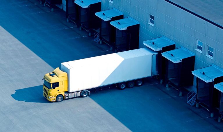 A single truck at the loading docks of a large warehouse