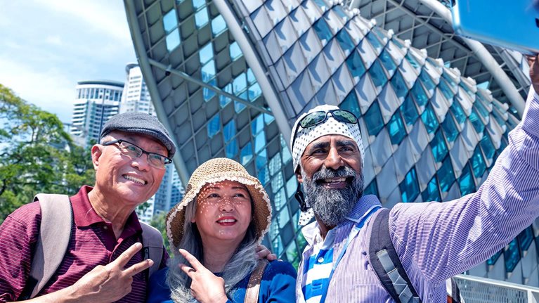 Image of two lovely senior Asian traveler having holiday photo taken by the Sikh tour guide in front of the Saloma Bridge, Kuala Lumpur.