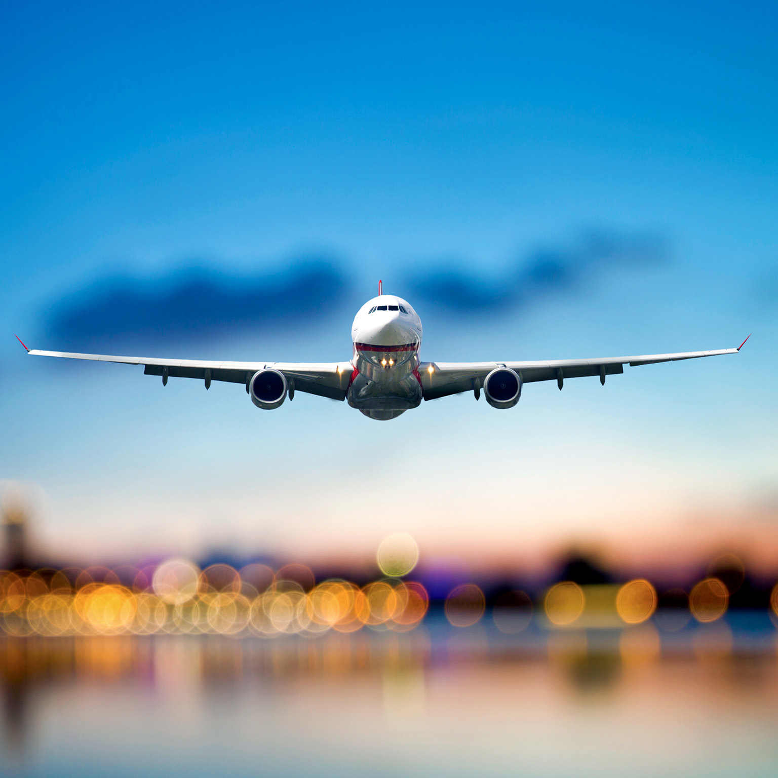Commercial airplane taking off, airport lights are blurred in the background