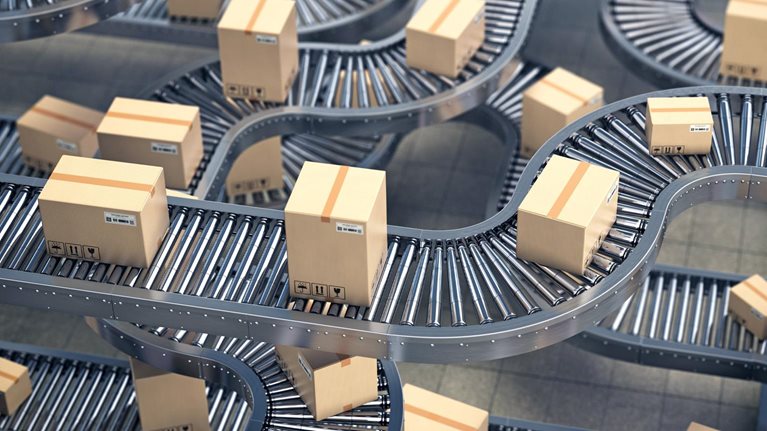 Cardboard boxes on conveyor roller in distribution warehouse