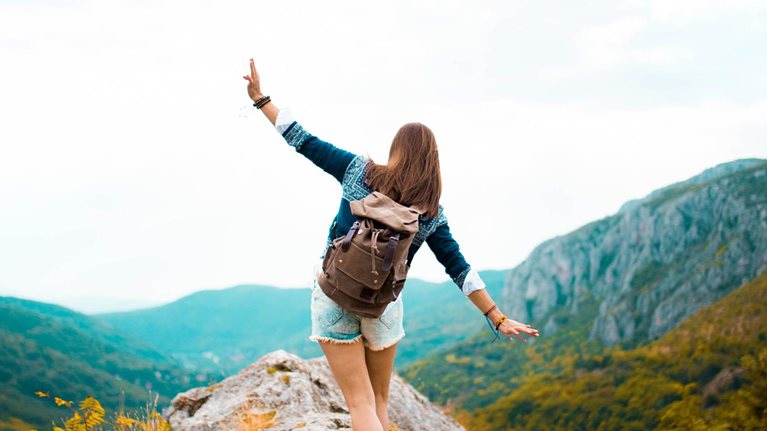 photo girl in hiking boot with backpack walking on rocks