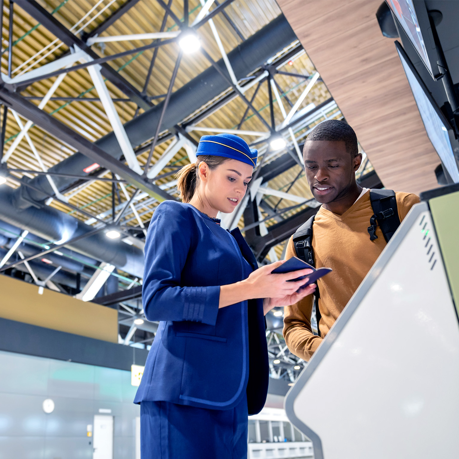 Airline attendant helping a traveler do the self check-in at the airport.