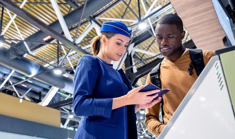 Airline attendant helping a traveler do the self check-in at the airport.