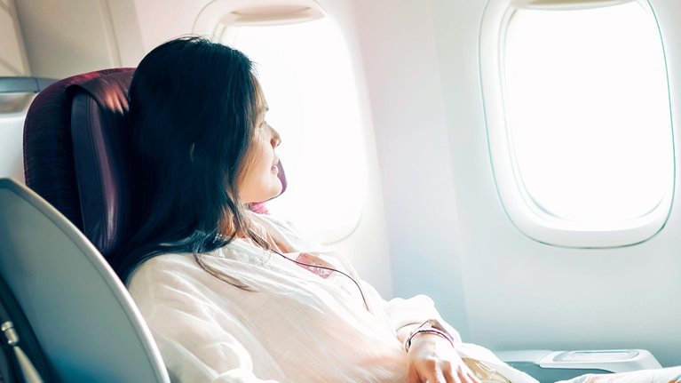 A relaxed business class passenger is looking out of the window of a passenger aircraft.