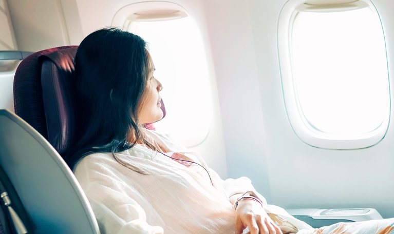 A relaxed business class passenger is looking out of the window of a passenger aircraft.