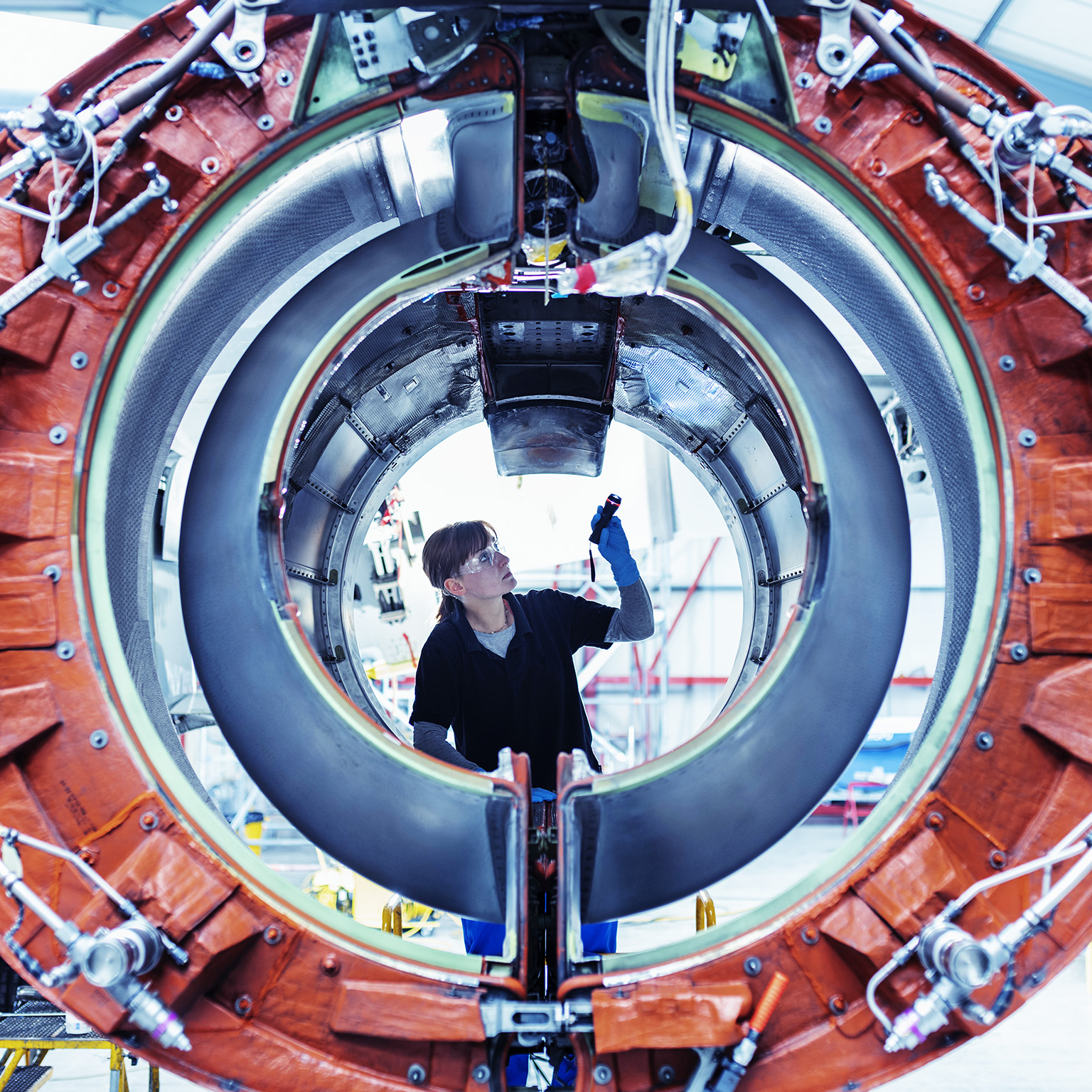 Image of an aircraft maintenance engineer inspecting a jet engine.