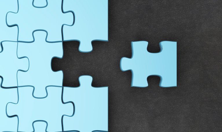 Jigsaw puzzle pieces. One fitting piece sitting outside of nearly completed puzzle.