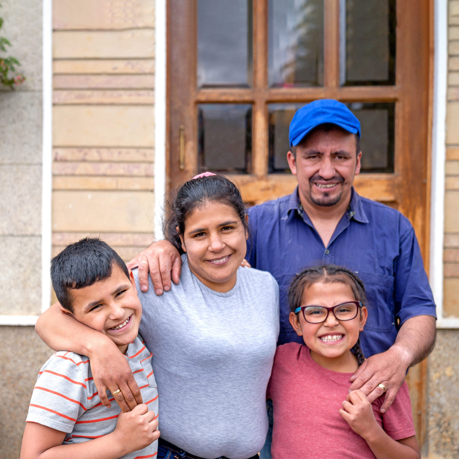 Portrait of a rural Latin American family in front of their new house and looking at the camera smiling