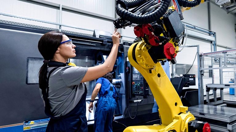 Maintenance engineer working in a factory using robotic arm