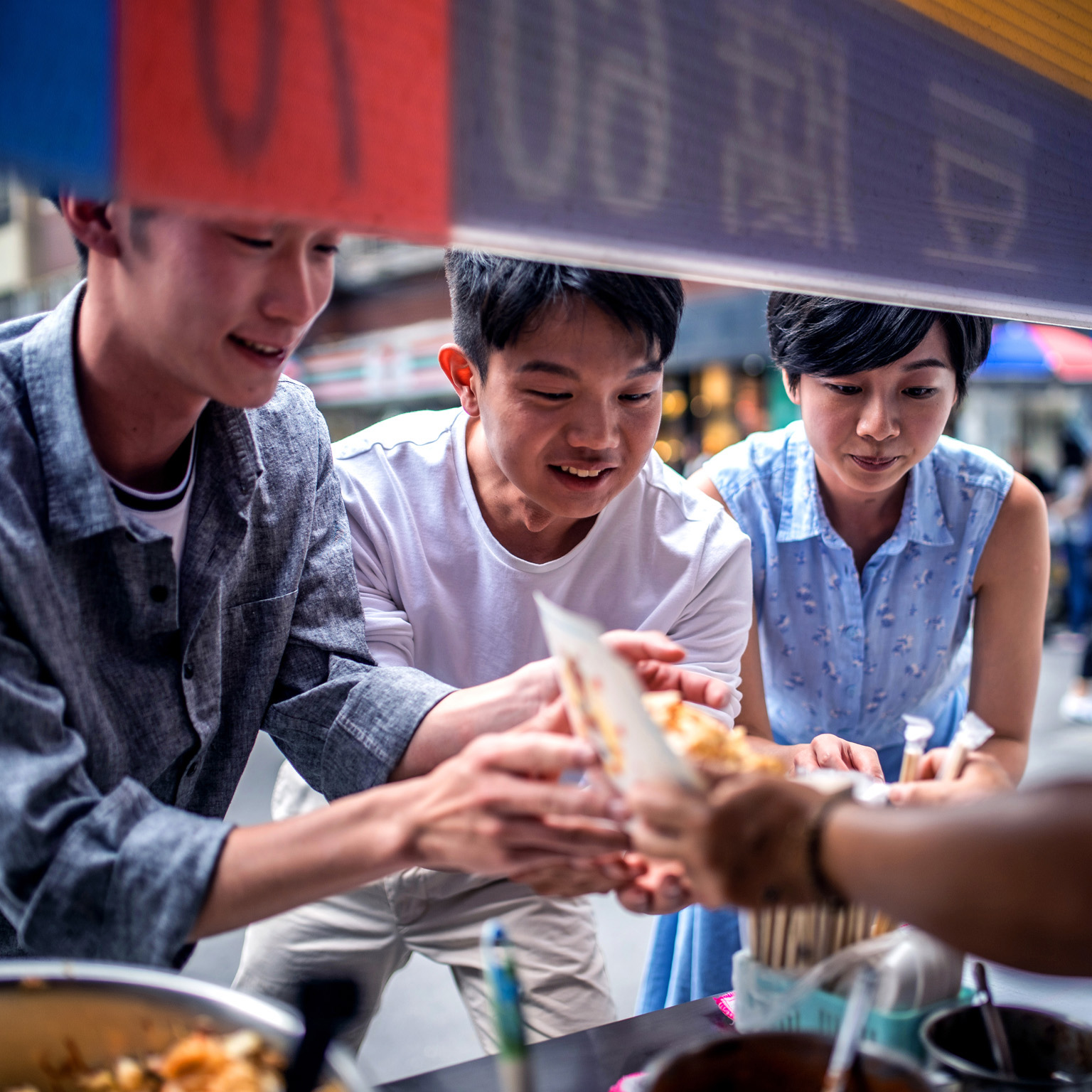 Three people ordering food at a street food counter