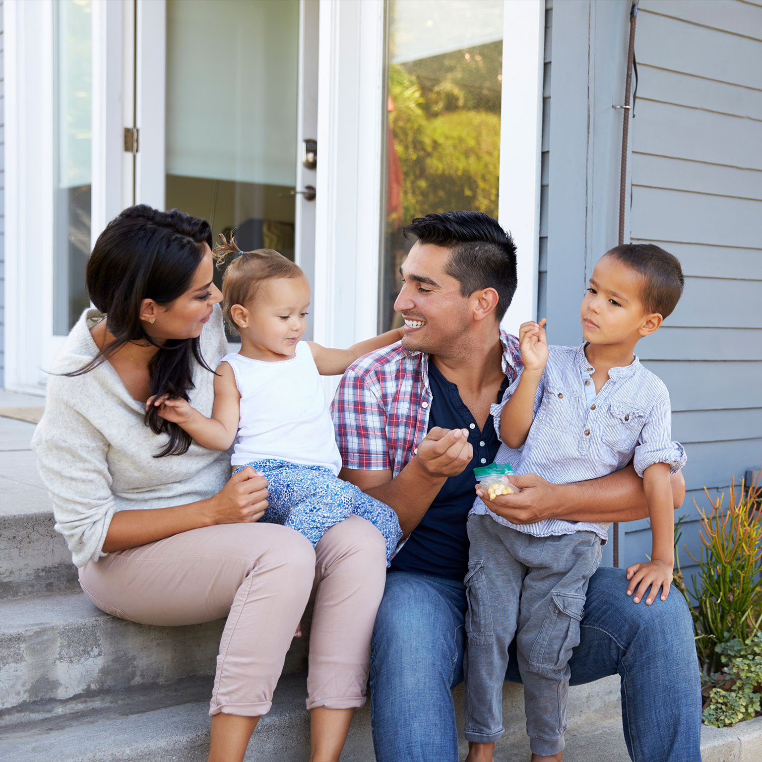 Father giving children candy on steps outside house