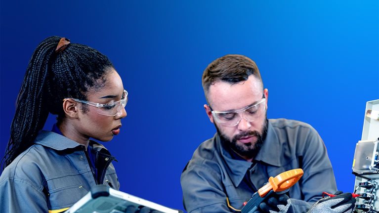Young man and woman in work coveralls and safety gear have a discussion in a warehouse.